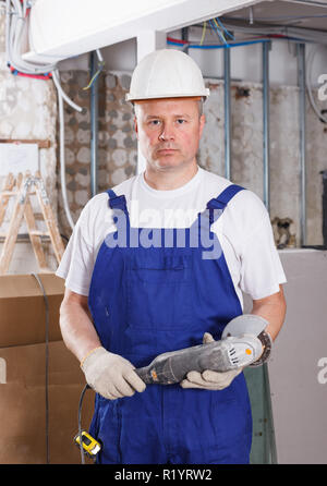 Construction worker using handheld circular saw at indoors building site Stock Photo