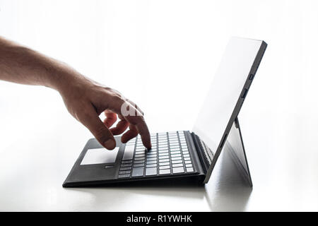 Compact laptop  tablet opened exposed keys pure white background hand and fingers finger pushing on key Stock Photo