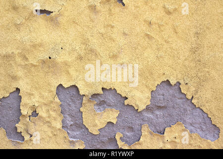 Yellow wall color peeling off because of water, grey plaster showing Stock Photo