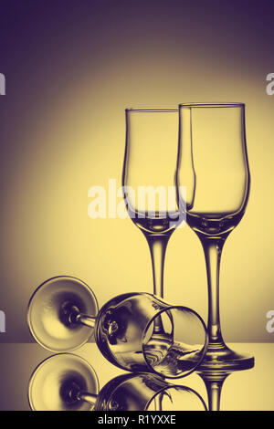 Three empty champagne glasses on colored background with reflection. Advertising image art toned Stock Photo