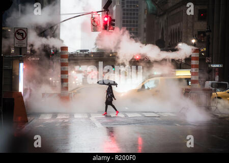 A woman with an umbrella and red high heels shoes is crossing the 42nd street in Manhattan. Taxi and steam coming out from from the manholes. Stock Photo
