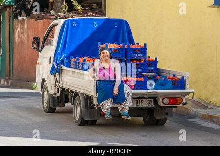 Istanbul, Turkey, November 13, 2012: Turkish woman riding on the back of a truck carrying crates of tomatoes. Stock Photo