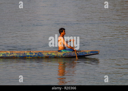 Don Det, Laos - April 22, 2018: Local man rowing a wooden long boat over the Mekong river in southern Laos Stock Photo
