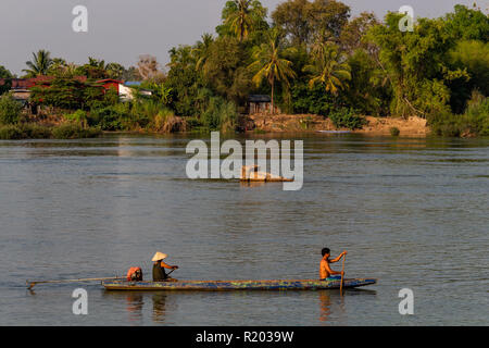 Don Det, Laos - April 22, 2018: Local people rowing a wooden long boat over the Mekong river in southern Laos Stock Photo