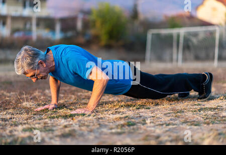 Senior Man doing pushups on an outdoor workout Stock Photo