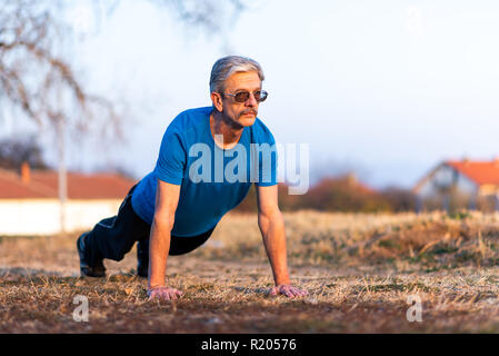 Senior Man doing pushups on an outdoor workout Stock Photo