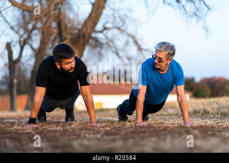 Senior father and son doing pushups on outdoor workout Stock Photo