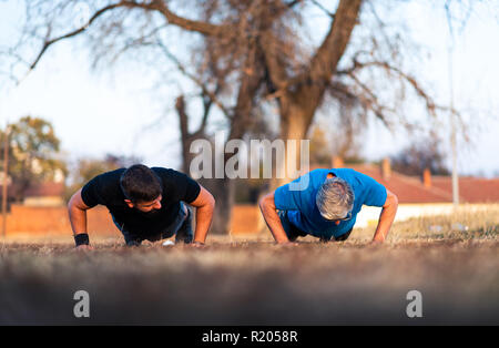 Senior father and son doing pushups on outdoor workout Stock Photo