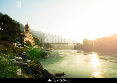 View of Ganga river embankment, Lakshman Jhula bridge and Tera Manzil Temple, Trimbakeshwar in Rishikesh during the sunset. India. Stock Photo