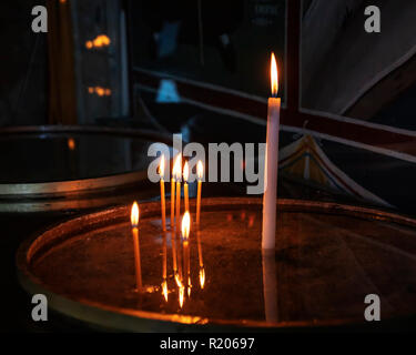 Burning church candles reflected on the surface of a silver tray. Greece Stock Photo