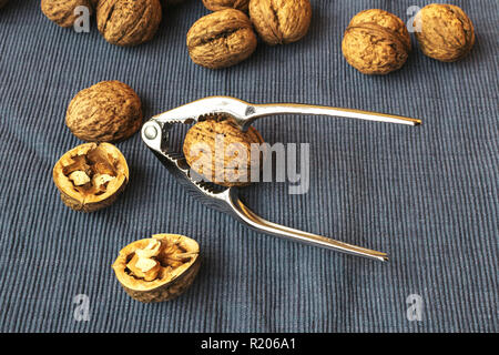 Walnuts with nutcracker. Cracking nuts on a dark background. Stock Photo