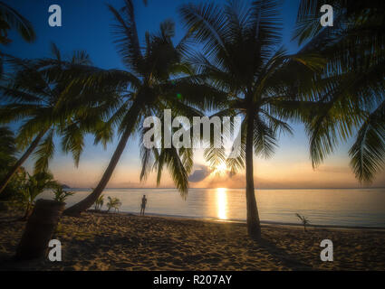 A tourist is watching an amazing sunset on a beautiful beach in Phuket, Thailand. Stock Photo