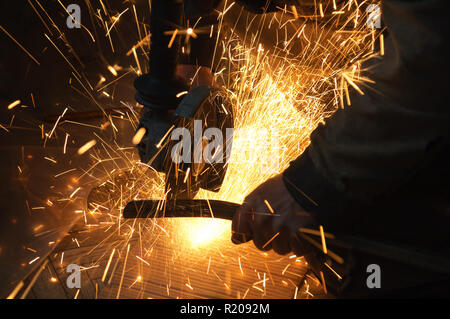 Worker at the plant. Sparks during operation of equipment. Stock Photo