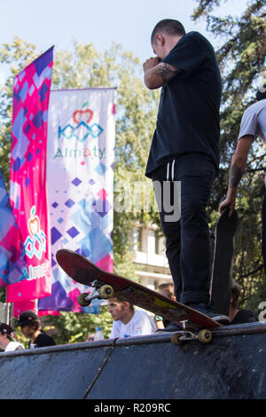 KAZAKHSTAN ALMATY - AUGUST 28, 2016: Urban extreme competition, where the city athletes compete in the disciplines: skateboard, roller skates, BMX. Skateboarder doing a trick in skate park Stock Photo