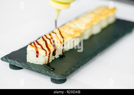 Putting sauce on uncut Japanese sushi roll Stock Photo