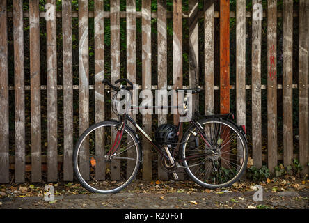 A black racing bicycle parked against a wooden fence with a black safety helmet in Berlin, wallpaper. Stock Photo