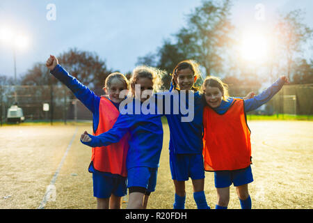 Portrait confident girls soccer team cheering on field Stock Photo