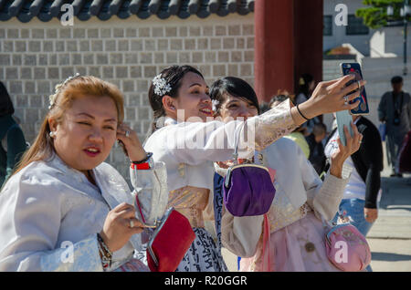 A couple of friends stop and take a selfie with a mobile phone whilst dressed up in traditional Korean dress, the hanbok. Stock Photo