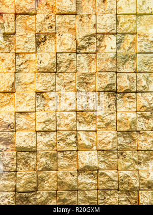 Bumpy golden small even squares brick wall background. Stock Photo