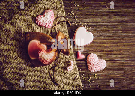 Various color hand made heart shape soaps on wooden board background, burlap cloth and in brown tulle gift bag. Hand made gift idea concept. Lot of co Stock Photo