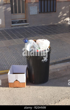A trash can and a cardboard box in the street waiting for garbage cans to pick it up Stock Photo