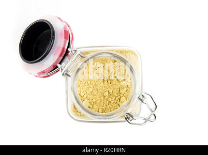 Dried yellow mustard powder in glass jar, isolated on white. Also Known As: Mustard Seed Powder. Isolated on white. Stock Photo