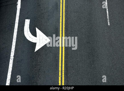 Yellow double solid line and turning arrow. Road markings on asphalt on the street of Manhattan in New York City Stock Photo