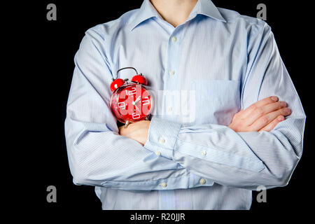 Adult male wearing formal shirt and hands crossed holding big red vintage alarm clock. Time concept. Stock Photo