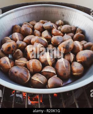 Roasted chestnuts in an iron pan cooked on the grill. Stock Photo