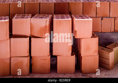Brick wall with a stack of new bricks, some broken Stock Photo