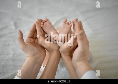 Mom and Dad are holding tenderly in the palms of the feet of a newborn baby Stock Photo