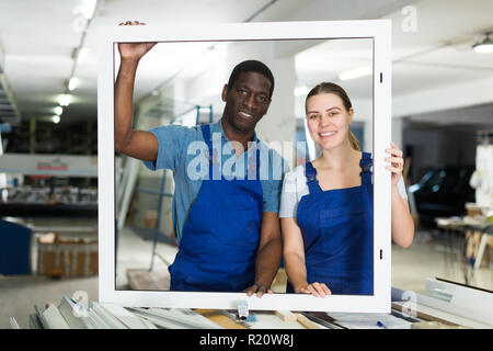 Two masters are working with window frame in the window workshop. Stock Photo