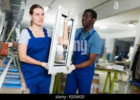 Two masters are working with window frame in the window workshop. Stock Photo