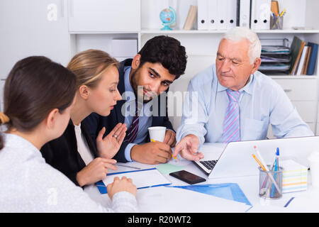 Managers are writing financial reports and discussing with mature boss in the office. Stock Photo
