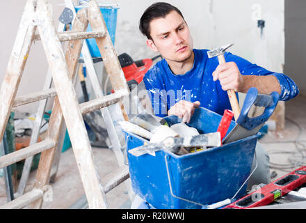 concentrated builder handyman choosing necessary tool in toolbox Stock Photo