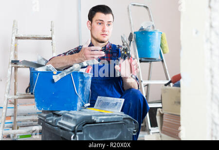 Young professional builder handyman choosing necessary tool in toolbox Stock Photo