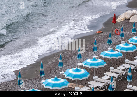 Rows of blue and white parasols and sunbeds on the beach at Atrani on the Amalfi Coast, Italy. Stock Photo