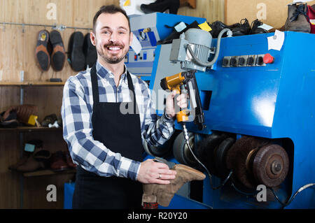 happy european male worker fixing failed shoes in shoe repair workshop Stock Photo