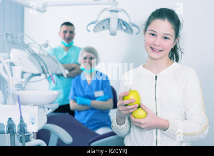 Portrait of happy teen girl in modern dental clinic with fresh apples in hands Stock Photo