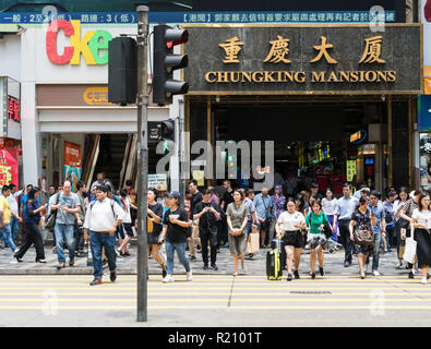 Hong Kong, China - May 16 2018:  People crossing the street in front of the famous Chungking Mansions in Tsim Sha Tsui, Kowloon in Hong Kong. Stock Photo