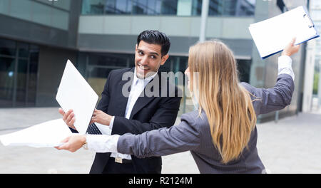 Portrait of businessman with his woman partner who are having fun with laptop outdoors near the office. Stock Photo