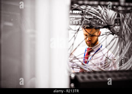 Technician checking cables in a rack mounted server Stock Photo