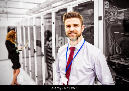 Smiling technician standing in a server room Stock Photo