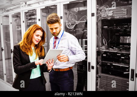 Technicians using digital tablet while analyzing server Stock Photo