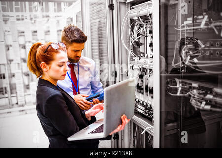 Technicians using laptop while analyzing server Stock Photo