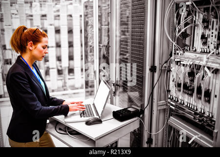 Technician using laptop while analyzing server Stock Photo