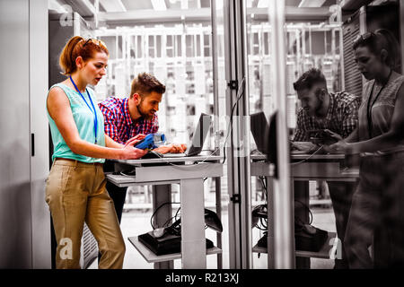 Technicians using laptop while analyzing server Stock Photo