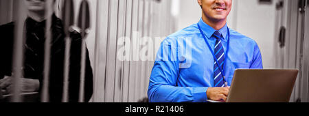 Portrait of technician using laptop while analyzing server Stock Photo