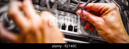 Technician plugging patch cable in a rack mounted server Stock Photo