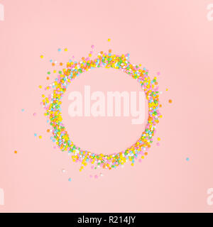 A circle of pastel star shaped sprinkles on a pink background with copy space Stock Photo